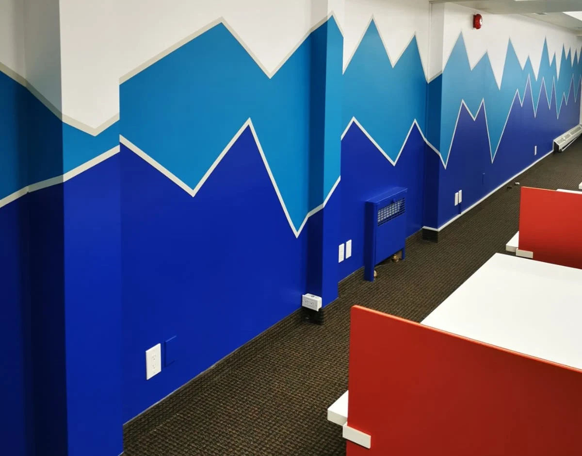 The same wall repainted as a layered mountain mural in three blues