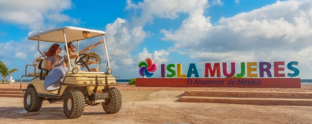 A couple in front of a Isla Mujeres sign