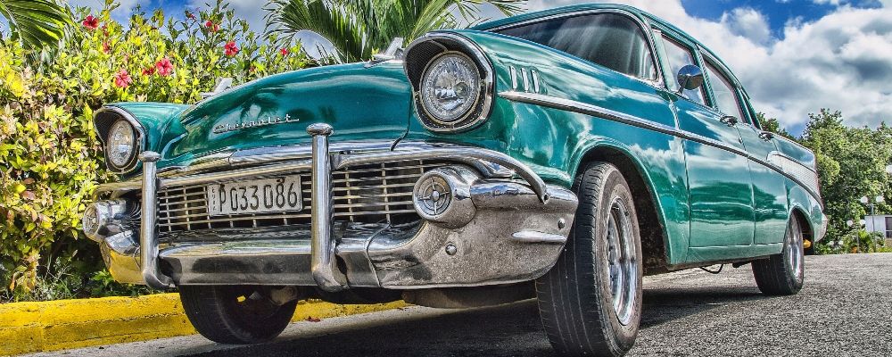 An old car parked near some bushes