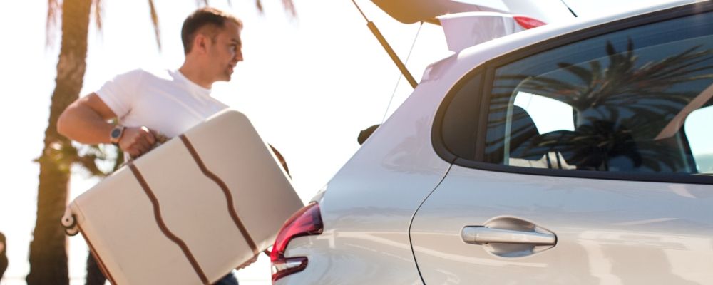 A man putting a suitcase in a car's trunk