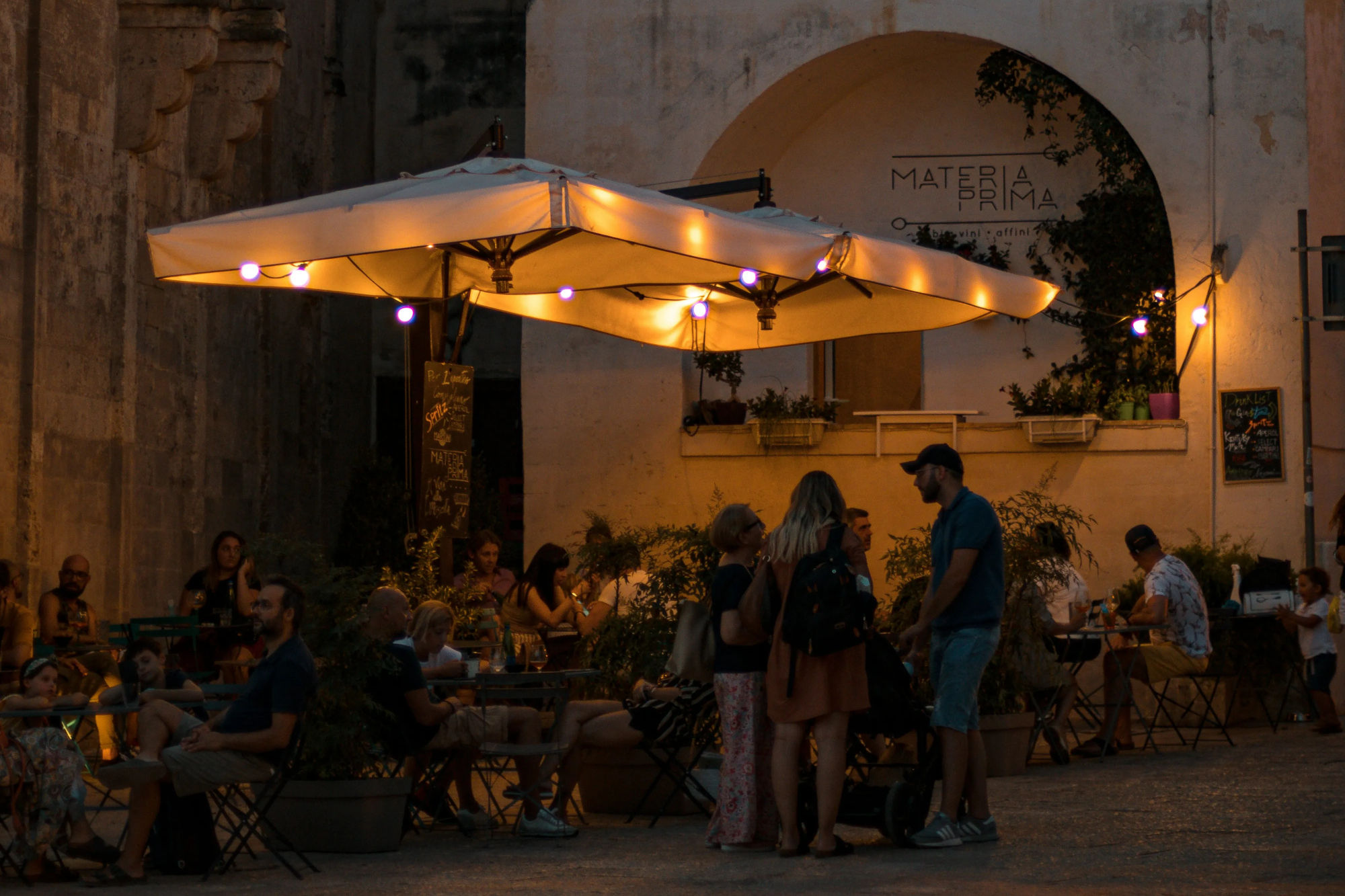 Individui seduti a tavoli, partecipando a discussioni e godendo della compagnia reciproca in un locale