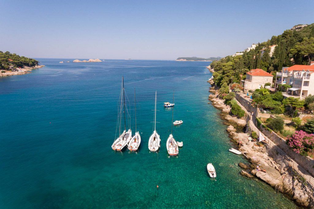 Four sailboats in crystal clear blue sea.