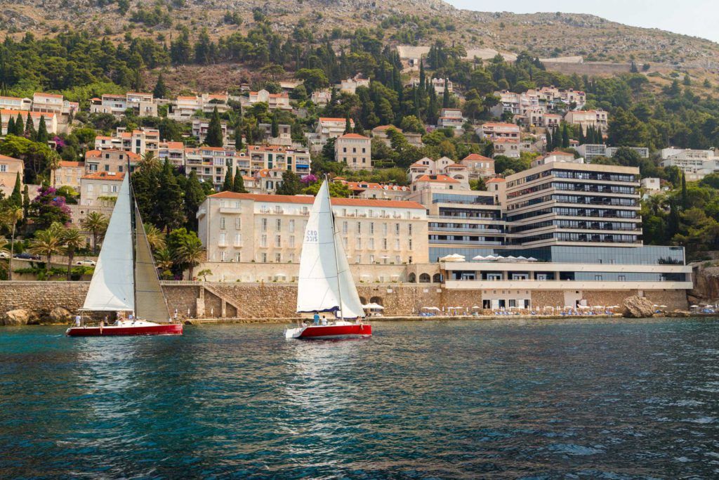 Two red sailboats with white sails in fron of the old town Dubrovnik in a Romantic sunset sailing around Dubrovnik