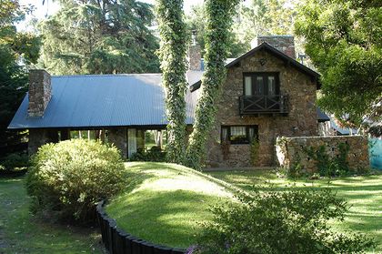 Casa rústica de piedra con vegetación exuberante — proyecto Casa Cariló 1997, por Hugo Zawadski Arquitectos, en Cariló