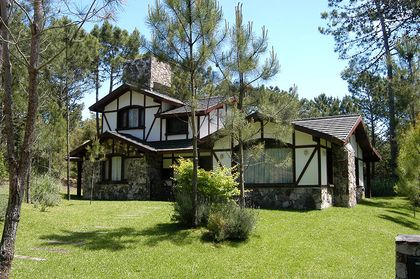 Casa rústica con fachada de piedra y madera en bosque — proyecto Casa Cariló 2003, por Hugo Zawadski Arquitectos, en Cariló