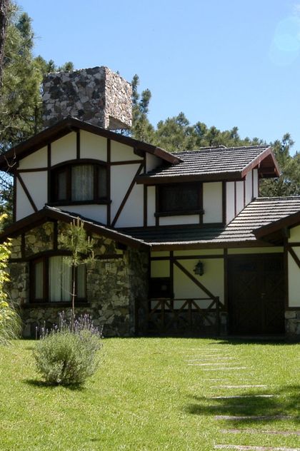 Fachada de casa estilo Tudor con detalles de piedra y madera — proyecto Casa Cariló 2003, por Hugo Zawadski Arquitectos, en Cariló
