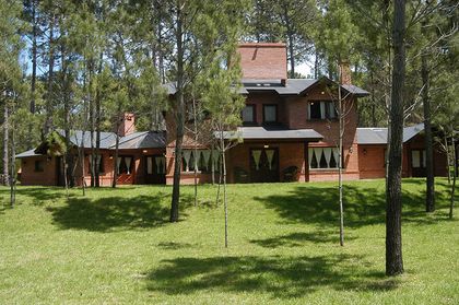Casa rústica de campo rodeada de bosque y con detalles de madera — proyecto Casa Cariló 2004, por Hugo Zawadski Arquitectos, en Cariló