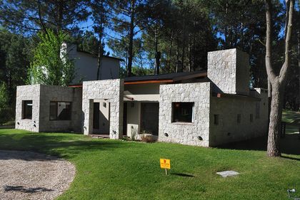 Fachada de casa moderna de piedra en bosque — proyecto Casa Cariló 2006, por Hugo Zawadski Arquitectos, en Cariló