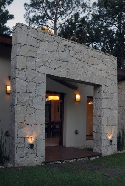 Entrada moderna con arco de piedra y deck de madera — proyecto Casa Cariló 2006, por Hugo Zawadski Arquitectos, en Cariló