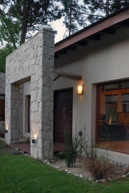 Fachada moderna con muro de piedra rústica y luces exteriores — proyecto Casa Cariló 2006, por Hugo Zawadski Arquitectos, en Cariló