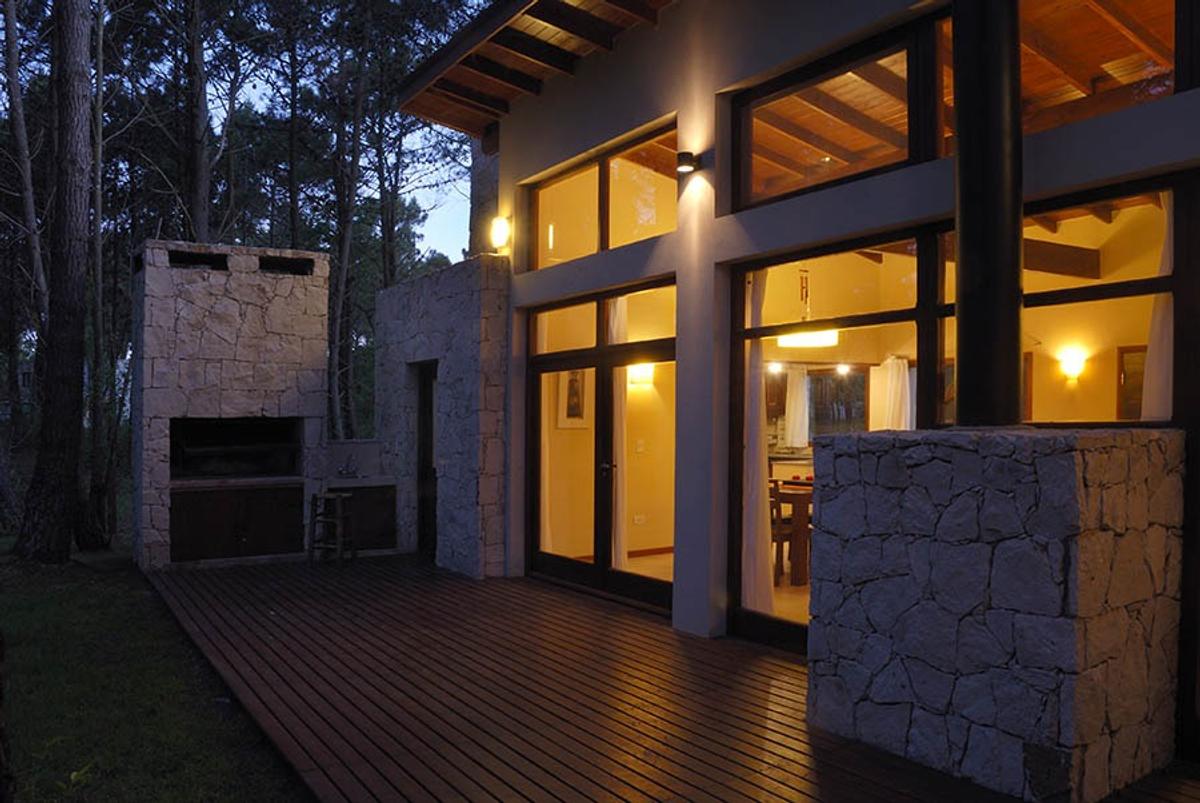 Fachada moderna com deck de madeira e churrasqueira integrada — projeto Casa Cariló 2006, por Hugo Zawadski Arquitectos, em Cariló