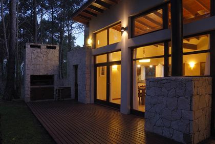 Fachada moderna con deck de madera y parrilla integrada — proyecto Casa Cariló 2006, por Hugo Zawadski Arquitectos, en Cariló