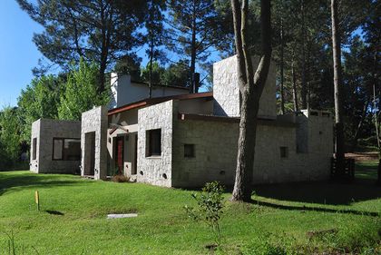 Casa moderna de piedra de estilo brutalista rodeada de árboles — proyecto Casa Cariló 2006, por Hugo Zawadski Arquitectos, en Cariló
