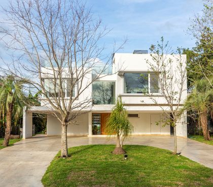 Fachada moderna con hormigón blanco, vidrio y vegetación — proyecto Las Caletas, por Arfuso Arquitectos, en Nordelta