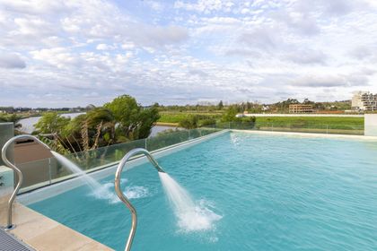 Piscina moderna con chorros de agua y vista al exterior — proyecto Las Caletas, por Arfuso Arquitectos, en Nordelta