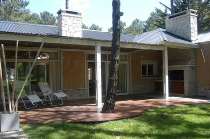 Fachada de casa moderna con patio de madera y vegetación — proyecto Casa Cariló 2005, por Hugo Zawadski Arquitectos, en Cariló