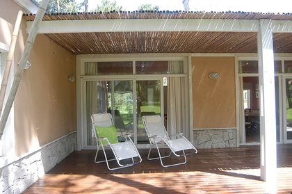 Porche de madera con sillones de descanso — proyecto Casa Cariló 2005, por Hugo Zawadski Arquitectos, en Cariló