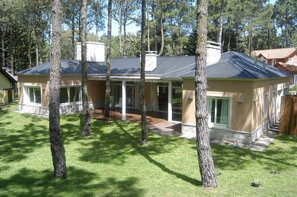 Fachada moderna con grandes ventanales y madera en entorno forestal — proyecto Casa Cariló 2005, por Hugo Zawadski Arquitectos, en Cariló