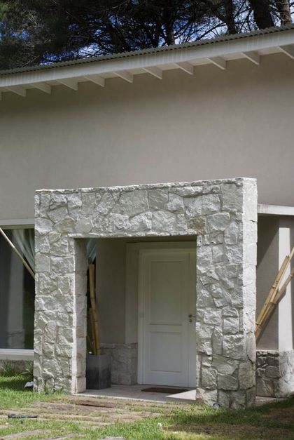 fachada moderna con entrada rústica de piedra — proyecto Casa Cariló 2007, por Hugo Zawadski Arquitectos, en Cariló