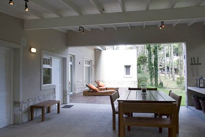 Pérgola moderna con comedor exterior y vista al bosque — proyecto Casa Cariló 2007, por Hugo Zawadski Arquitectos, en Cariló