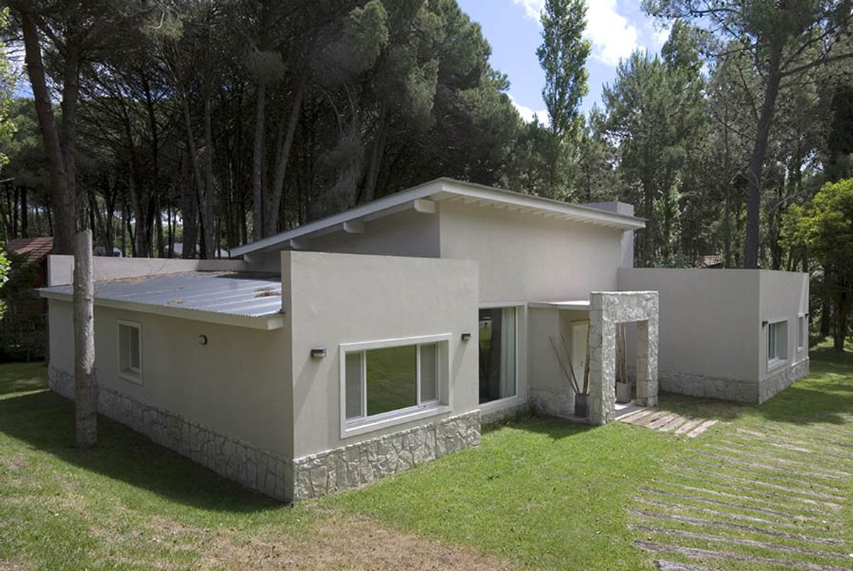 fachada moderna com base de pedra cercada por floresta — projeto Casa Cariló 2007, por Hugo Zawadski Arquitectos, em Cariló