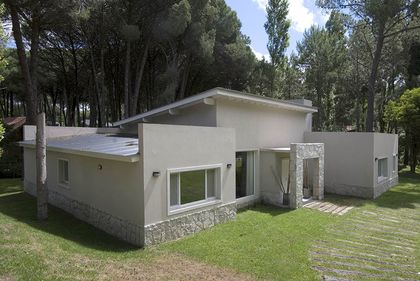fachada moderna con base de piedra rodeada de bosque — proyecto Casa Cariló 2007, por Hugo Zawadski Arquitectos, en Cariló