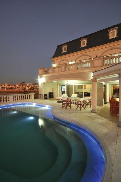 piscina iluminada frente a mansión con techo mansarda estilo clásico — proyecto Casa 4, por Fhee Construcciones, en Nordelta