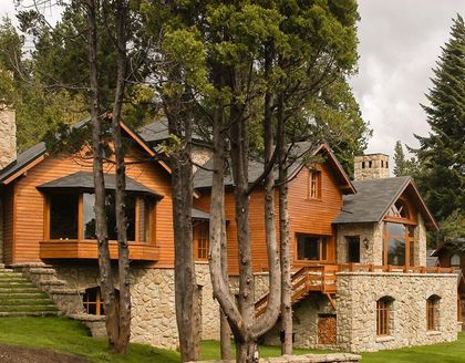 Fachada de casa rústica moderna de madera y piedra en montaña — proyecto Corrientes del Nahuel, por Ricardo Pereyra Iraola , en Bariloche