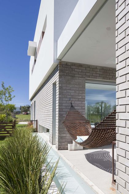 Fachada moderna con detalles de ladrillo y silla colgante — proyecto Casa MA, por Estudio GR, en City Bell