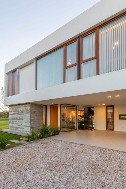 Fachada moderna con hormigón visto y grandes ventanales de madera — proyecto Casa ME, por Estudio GR, en City Bell