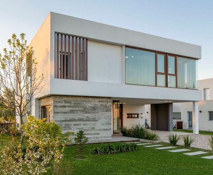 Fachada moderna con detalles en piedra y madera, amplios ventanales — proyecto Casa ME, por Estudio GR, en City Bell