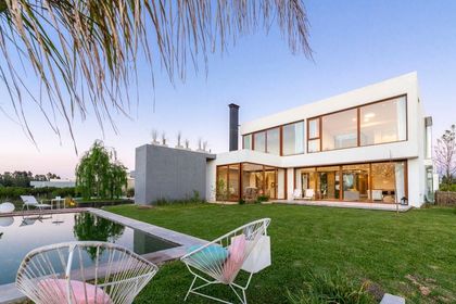 Moderna casa con piscina y amplios ventanales al atardecer — proyecto Casa ME, por Estudio GR, en City Bell