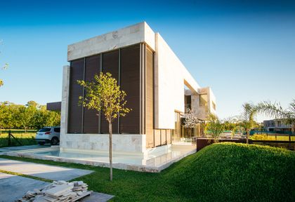 Fachada moderna de casa con líneas geométricas y amplios ventanales — proyecto Grand Bell 60, por Mercedes  klappenbach, en City Bell
