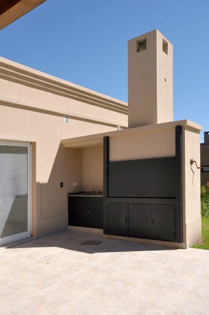 quincho moderno con parrilla integrada y patio de baldosas — proyecto Casa 11, por Estudio Martínez Nespral