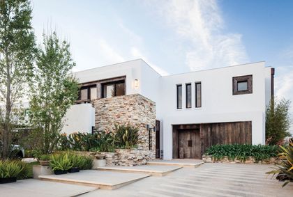 Fachada moderna con contraste de piedra y madera, amplias ventanas — proyecto Casa DFS, por Estudio Gamboa