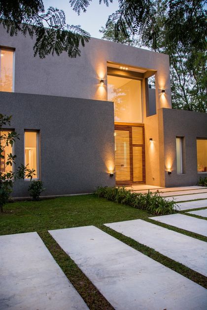 Casa moderna gris con entrada iluminada y jardín de noche — proyecto Casa 18, por Parrado Arquitectura