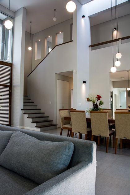 Escalera moderna doble altura iluminada con lámparas pendant en vivienda contemporánea — proyecto Casa 18, por Parrado Arquitectura