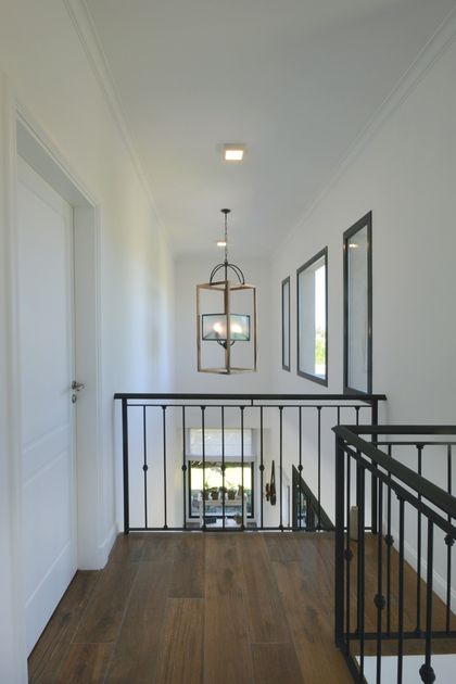 Pasillo luminoso con escalera negra y piso de madera clara — proyecto Casa 16, por Parrado Arquitectura