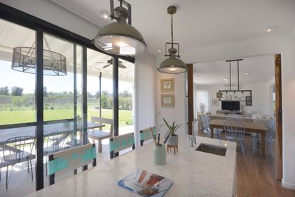 Comedor moderno con isla, grandes ventanales y vista al campo — proyecto Casa 16, por Parrado Arquitectura