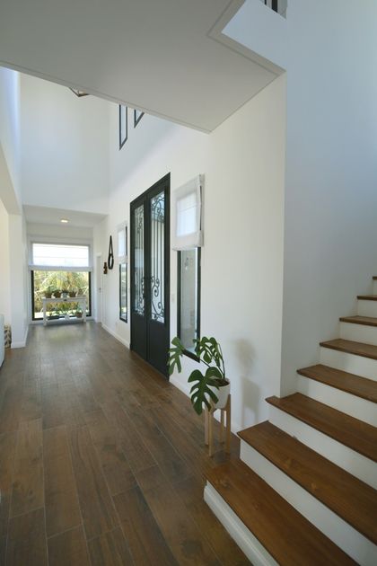Pasillo moderno con escalera de madera blanca y doble altura luminosa — proyecto Casa 16, por Parrado Arquitectura