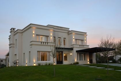Casa moderna de dos pisos con fachada blanca iluminada al atardecer — proyecto Casa 17, por Parrado Arquitectura