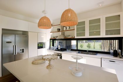Cocina moderna con isla central, lámparas colgantes y ventanal luminoso — proyecto Casa 15, por Parrado Arquitectura
