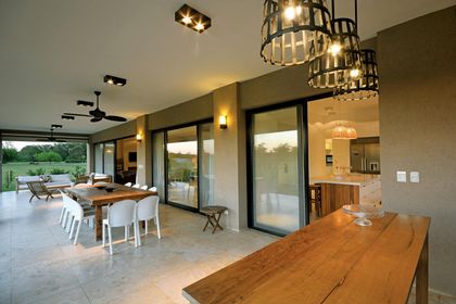 Comedor amplio con mesada madera, ventanales grandes y cocina abierta — proyecto Casa 15, por Parrado Arquitectura