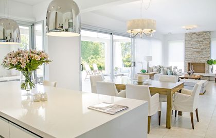 Cocina moderna blanca con isla de mármol y amplios ventanales — proyecto Casa 13, por Parrado Arquitectura