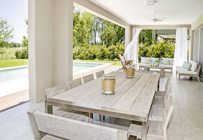 Galería abierta con mesa de madera, pileta y jardín al fondo — proyecto Casa 13, por Parrado Arquitectura
