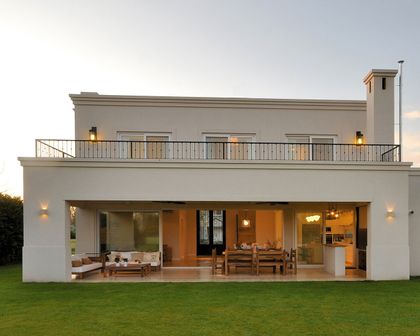 Casa moderna blanca con terraza cubierta y jardín al atardecer — proyecto Casa 12, por Parrado Arquitectura