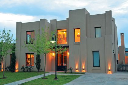 Casa moderna gris con iluminación nocturna y jardín diseñado — proyecto Casa 10, por Parrado Arquitectura