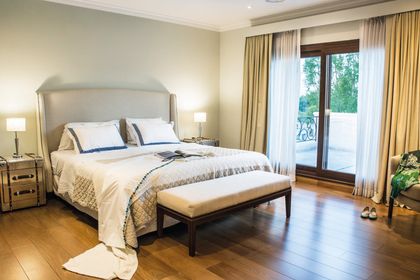 Dormitorio luminoso con cama tapizada, piso de madera y balcón — proyecto TRV 164, por Estudio Arq Daniel Tarrio