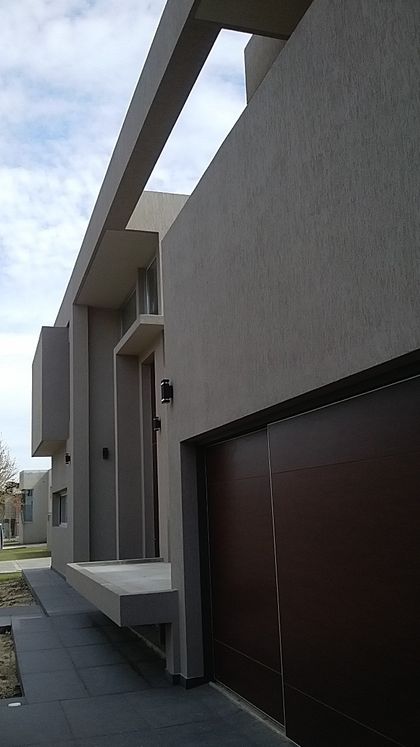 Fachada moderna gris de hormigón con detalles en madera oscura — proyecto Grand Bell, por Gabellini-Rey arquitectos, en City Bell