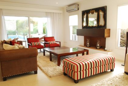 Living moderno con sillones rojos, mesa baja y puf a rayas — proyecto VO 38, por Estudio Arq Daniel Tarrio